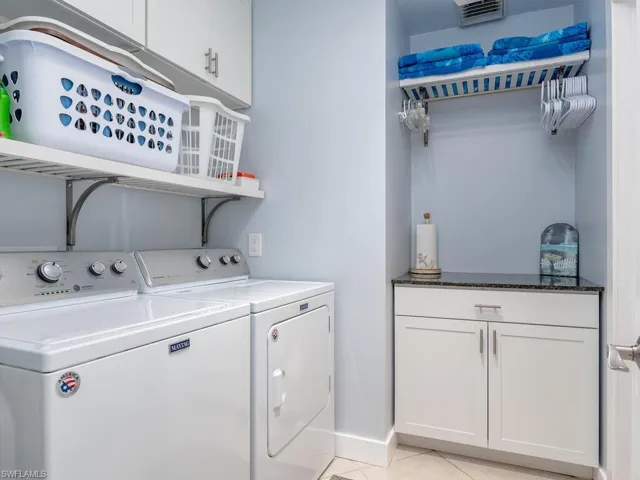 Washroom featuring independent washer and dryer, cabinet space, and light tile patterned floors
