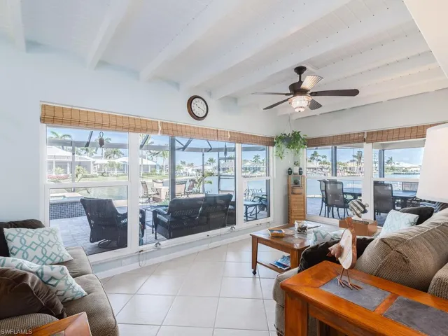 Living area featuring beam ceiling, a ceiling fan, and light tile patterned flooring