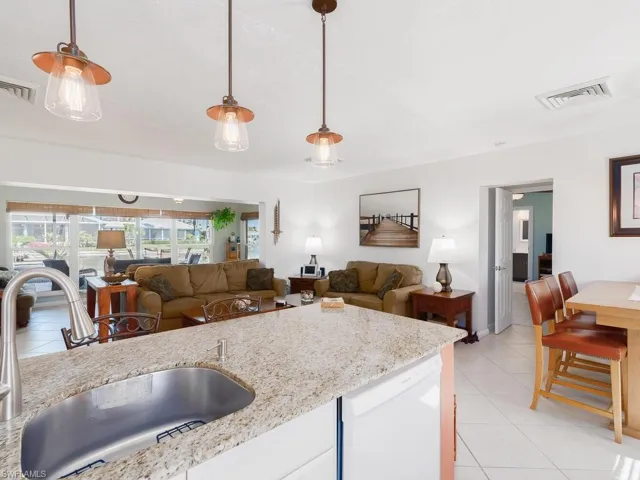 Kitchen featuring a sink, dishwasher, light tile patterned floors, and decorative light fixtures