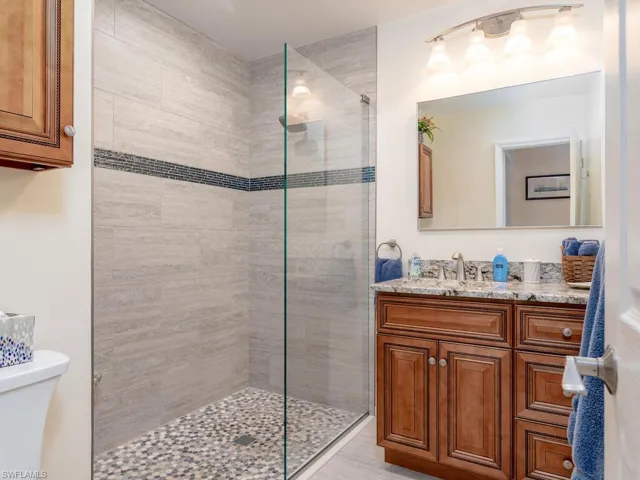 Bathroom with a tile shower, toilet, and vanity