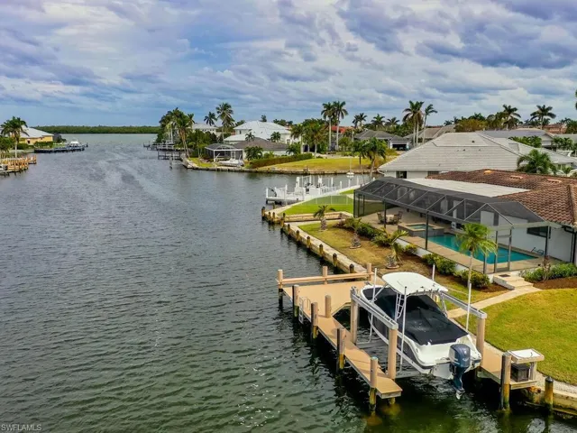 Dock with boat lift, a water view, a lanai, and a pool with connected hot tub