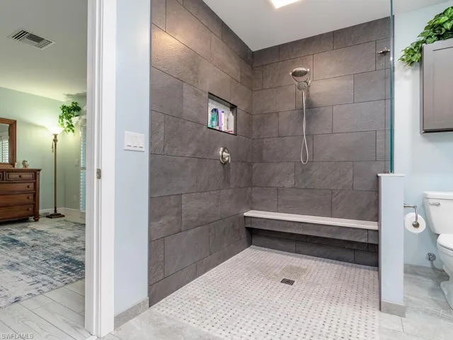 Bathroom with toilet, a walk in shower, and vanity