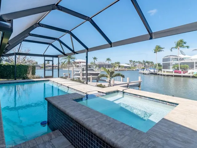 View of swimming pool featuring a boat dock, a water view, boat lift, and glass enclosure