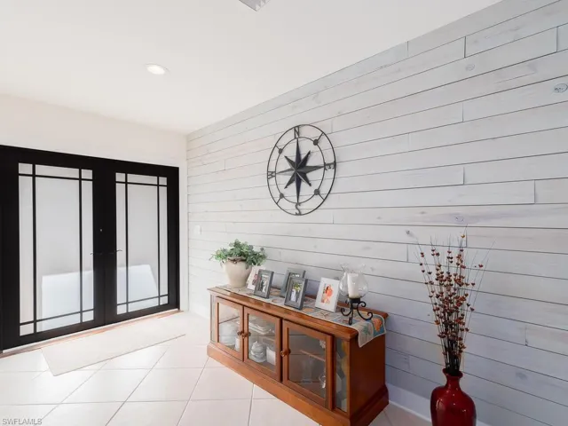 Hall with light tile patterned floors, wood walls, french doors, and recessed lighting