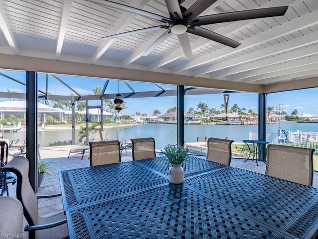 View of patio / terrace featuring a water view, outdoor dining area, a ceiling fan, and glass enclosure