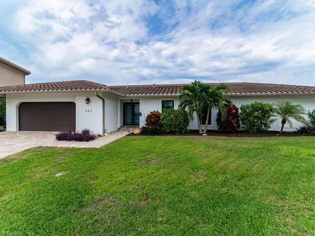 Mediterranean / spanish-style home featuring concrete driveway, a garage, stucco siding, a tile roof, and a front yard