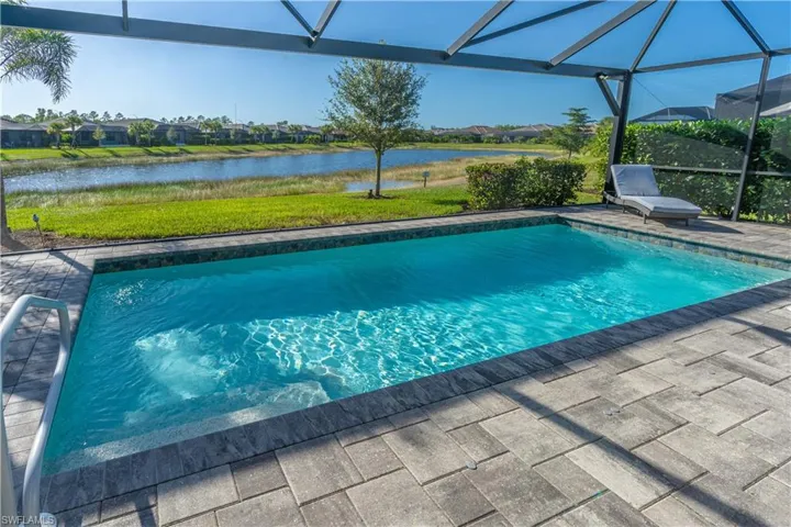 View of pool with a patio, a water view, and glass enclosure