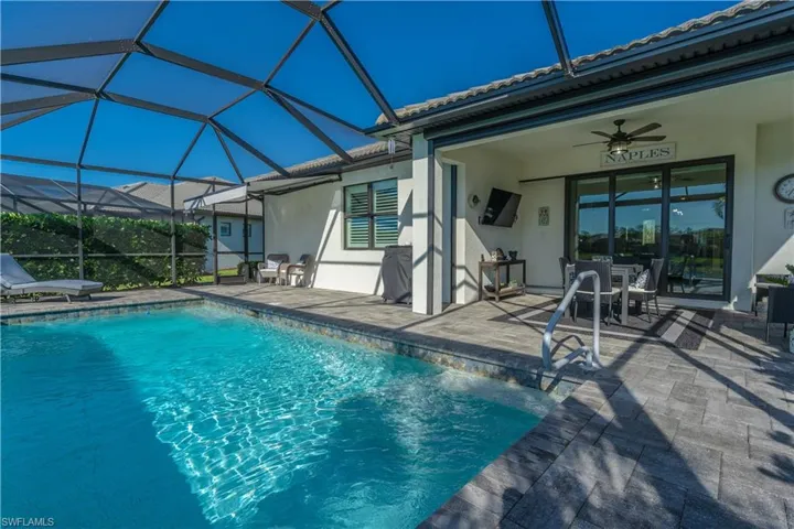 View of swimming pool featuring ceiling fan, a patio area, and glass enclosure