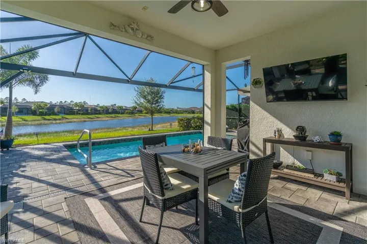 View of patio with ceiling fan, a water view, and glass enclosure