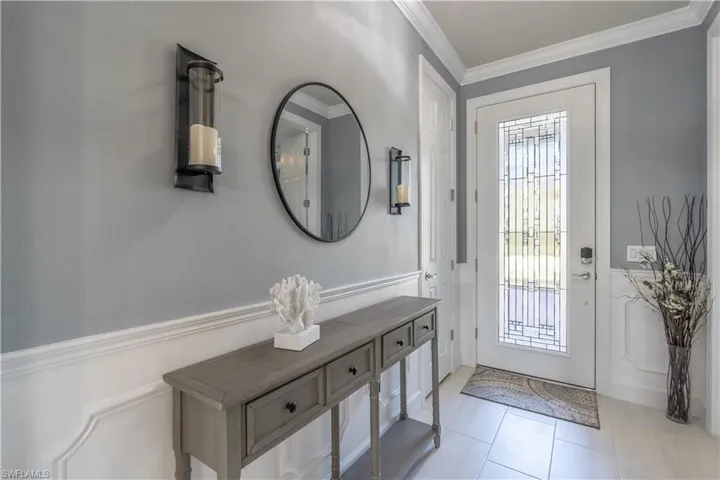 Foyer entrance featuring light tile patterned floors and ornamental molding