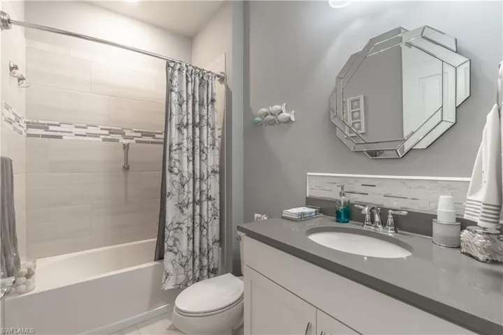 Full bathroom with backsplash, vanity, shower / bath combo, and toilet