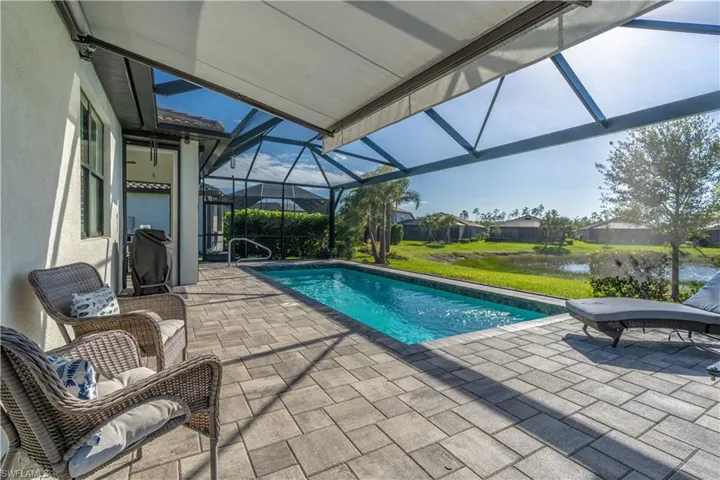 View of pool featuring a water view, glass enclosure, and a patio area