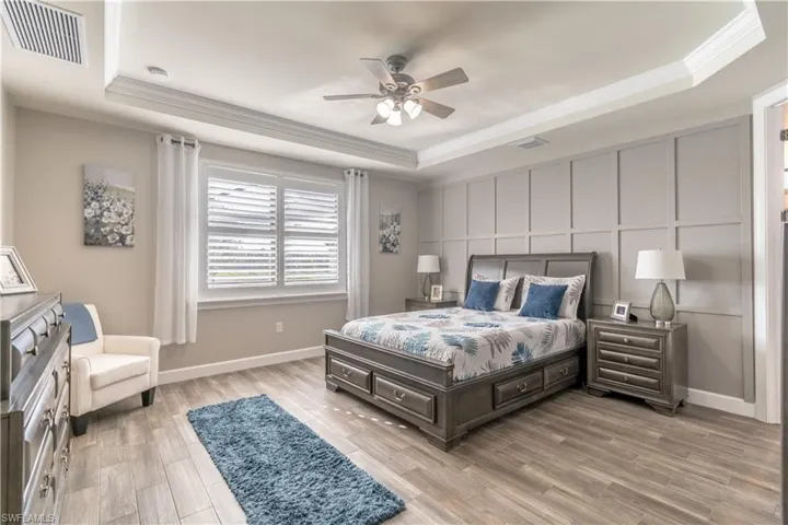 Bedroom featuring a tray ceiling, light hardwood / wood-style flooring, and ceiling fan