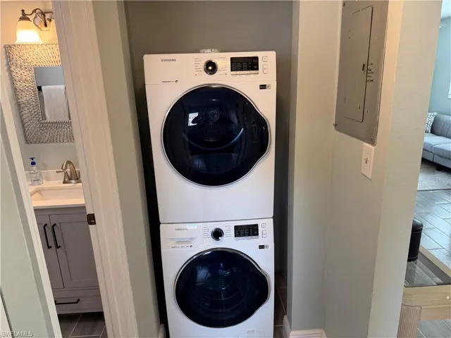 Laundry area featuring electric panel and stacked washer / drying machine