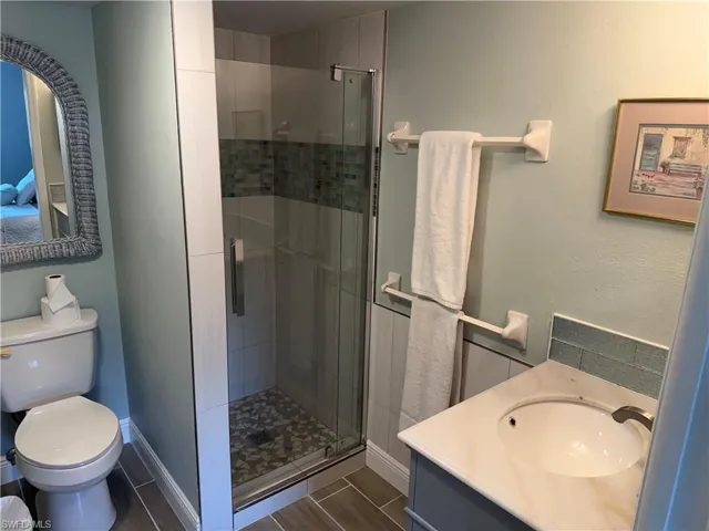 Full bath featuring vanity, a shower stall, and wood finish floors