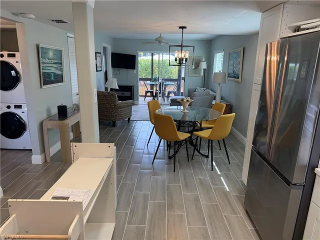 Dining room with wood finish floors, stacked washing machine and dryer, a ceiling fan, and a chandelier
