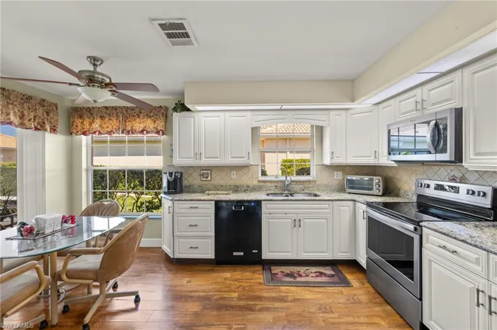 Kitchen featuring tasteful backsplash, visible vents, appliances with stainless steel finishes, wood finished floors, and a sink