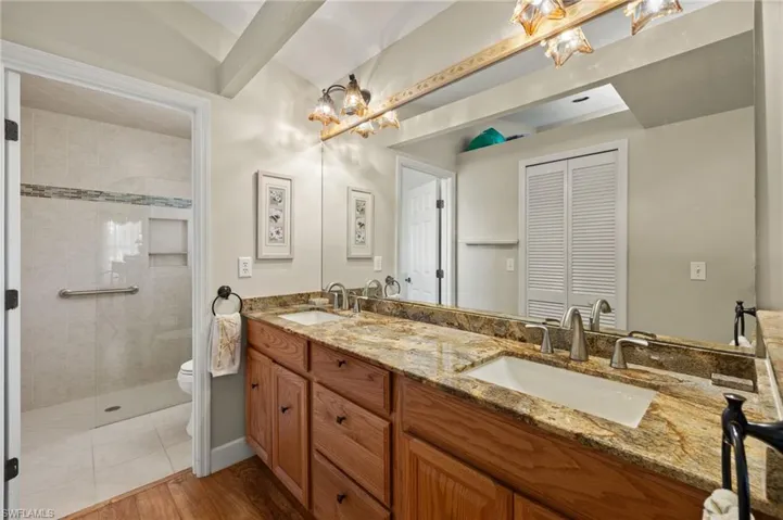 Full bath with a sink, toilet, double vanity, and a tile shower