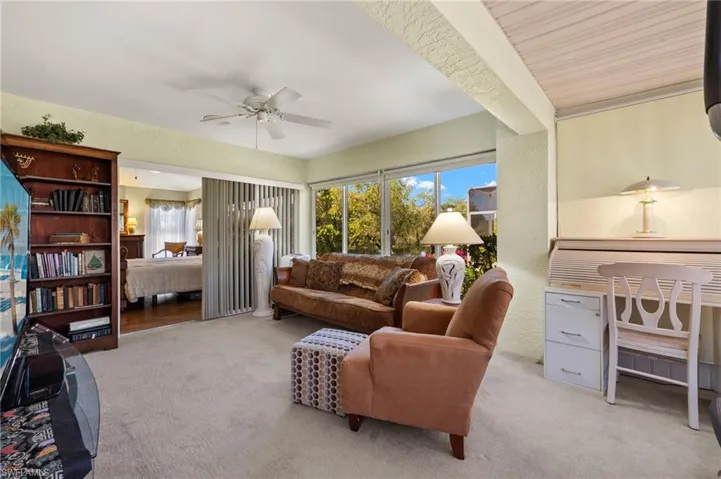 Carpeted living area featuring a wealth of natural light, ceiling fan, and a textured wall