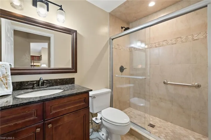 Full bathroom with a shower stall, toilet, and vanity