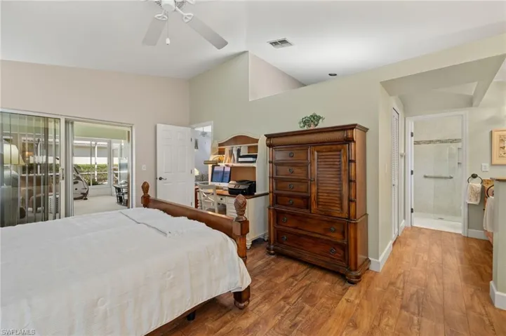 Bedroom featuring visible vents, a ceiling fan, wood finished floors, baseboards, and vaulted ceiling