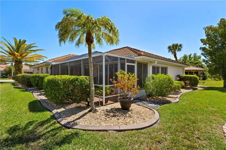 Back of house with a lawn, a tile roof, glass enclosure, and stucco siding