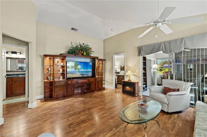 Living room with visible vents, a fireplace, wood finished floors, high vaulted ceiling, and a ceiling fan