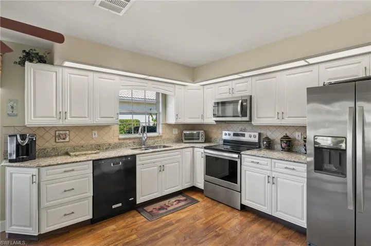 Kitchen with visible vents, a sink, dark wood-type flooring, appliances with stainless steel finishes, and white cabinetry