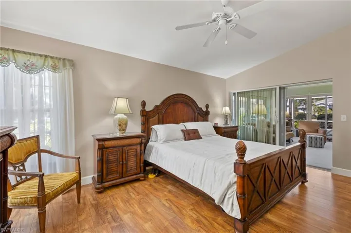 Bedroom with lofted ceiling, access to outside, wood finished floors, and baseboards