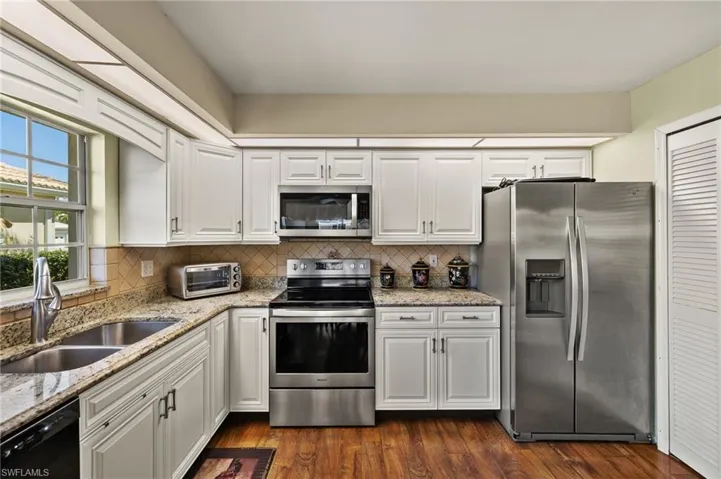 Kitchen with a sink, stainless steel appliances, tasteful backsplash, and white cabinetry