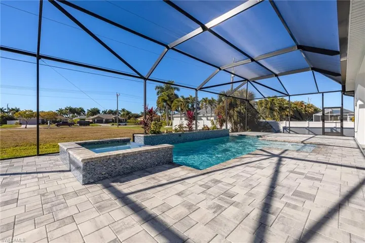 View of pool with a sunroom, a pool with connected hot tub, glass enclosure, and a patio