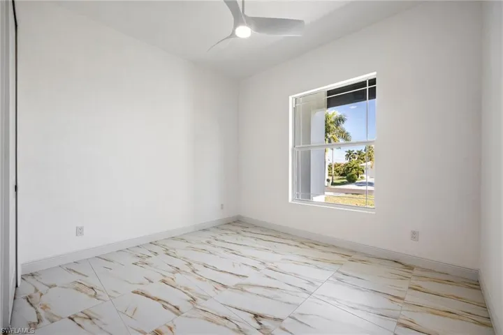 Spare room featuring light marble finish floors and a ceiling fan