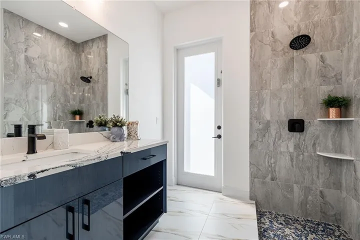 Full bathroom featuring light marble finish flooring, vanity, and walk in shower