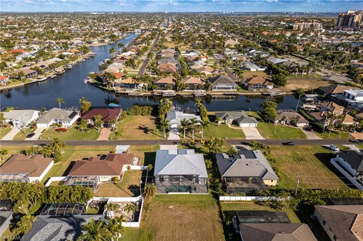 Aerial view of property and surrounding area featuring nearby suburban area and a nearby body of water