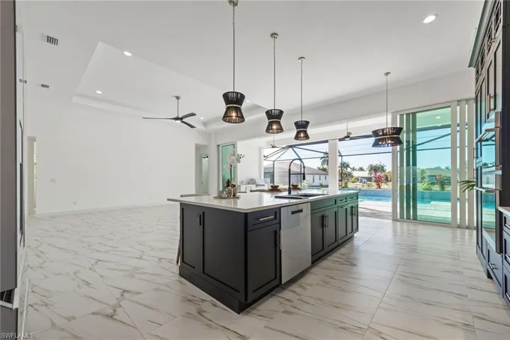 Kitchen featuring recessed lighting, open floor plan, pendant lighting, light marble finish flooring, and dishwasher
