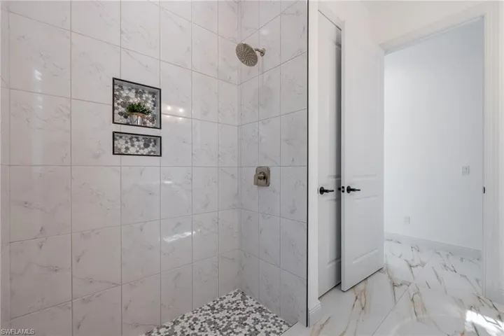Bathroom featuring marble finish flooring and tiled shower