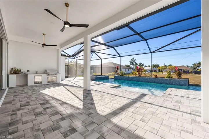 View of swimming pool with a sunroom, a patio, glass enclosure, exterior kitchen, and a pool with connected hot tub