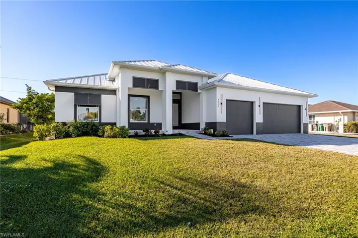 Prairie-style house with decorative driveway, a metal roof, a front yard, a standing seam roof, and stucco siding