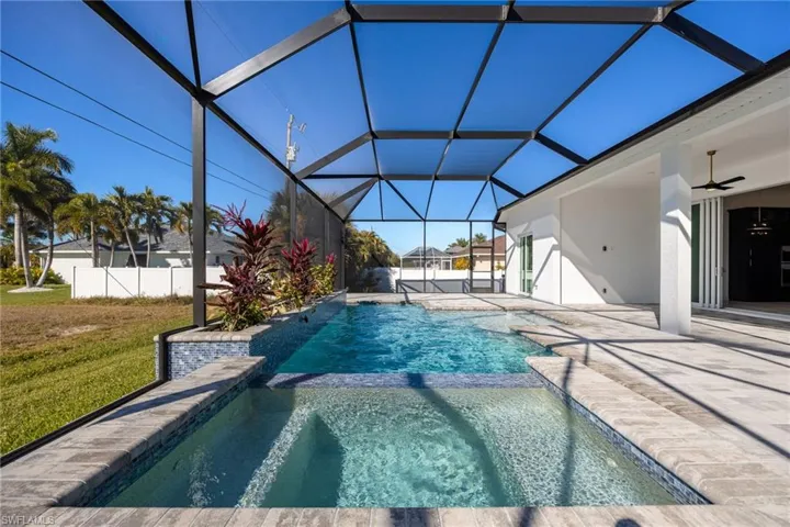 View of swimming pool featuring a sunroom, glass enclosure, a patio, and a pool with connected hot tub