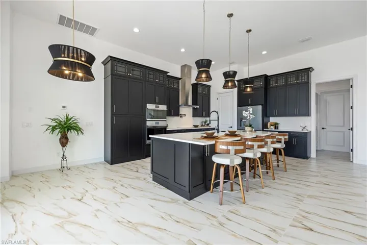 Kitchen with dark cabinetry, a breakfast bar area, hanging light fixtures, and recessed lighting