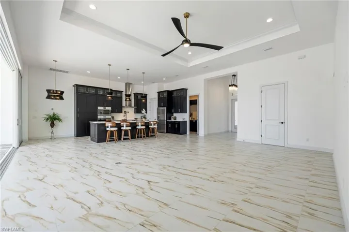 Kitchen featuring light countertops, a breakfast bar area, open floor plan, a kitchen island with sink, and dark cabinets