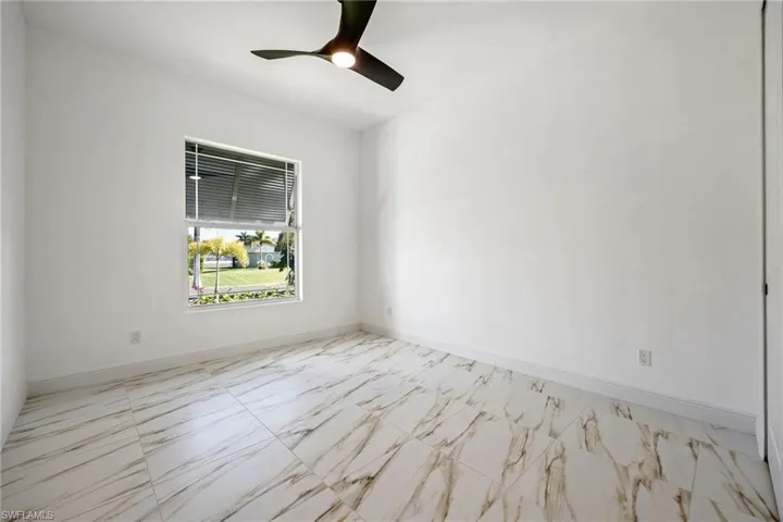 Spare room with light marble finish floors and ceiling fan