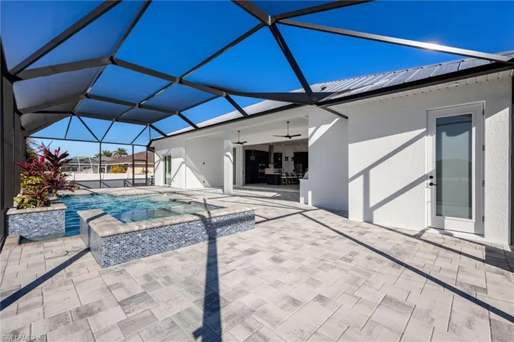 Swimming pool featuring glass enclosure, a patio area, an outdoor hot tub, and a sunroom