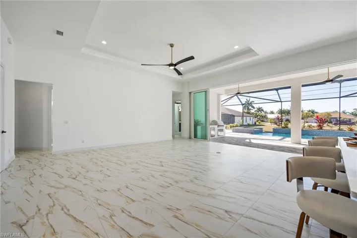 Living area with a sunroom, light marble finish flooring, a raised ceiling, recessed lighting, and a ceiling fan