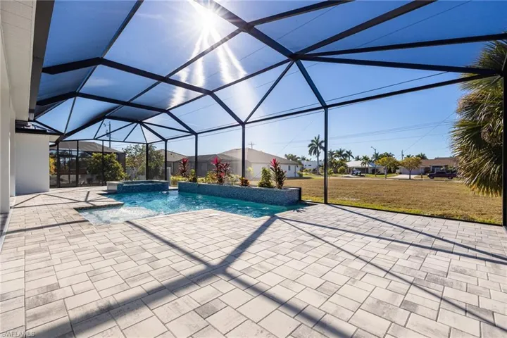 View of swimming pool with a sunroom, a pool with connected hot tub, glass enclosure, a patio, and a lawn
