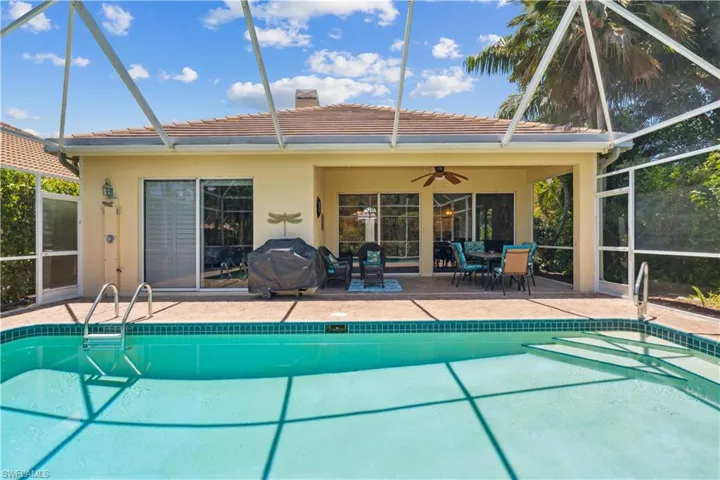 View of swimming pool with ceiling fan, glass enclosure, area for grilling, and a patio