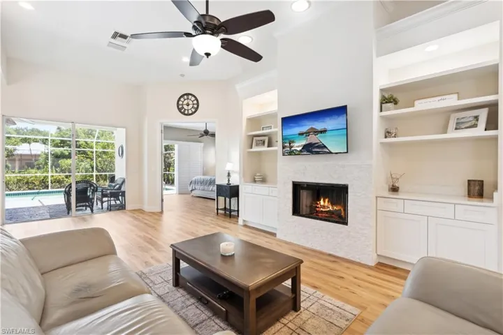 Living room with built in features, ceiling fan, and light hardwood / wood-style floors
