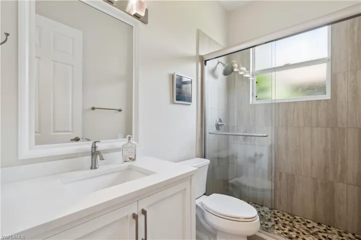 Bathroom featuring a shower with shower door, large vanity, and toilet
