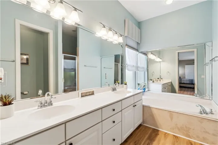 Bathroom with a bath, double sink vanity, and wood-type flooring