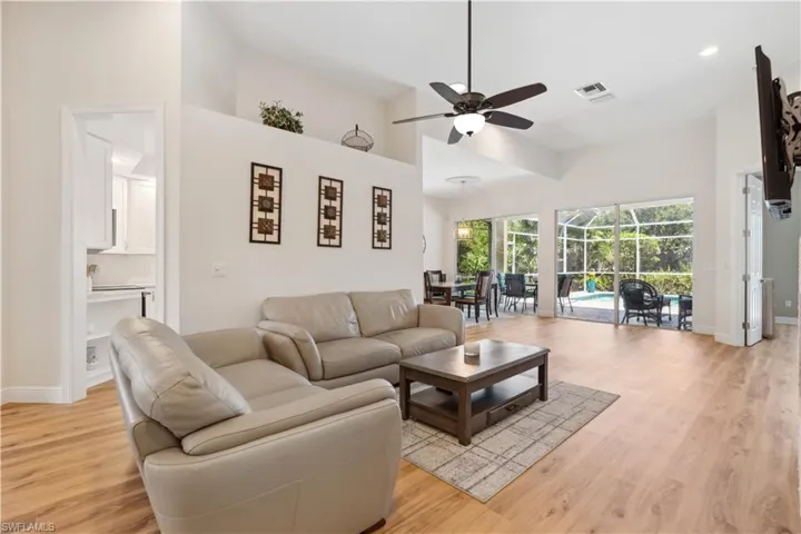 Living room with ceiling fan, a high ceiling, and light hardwood / wood-style flooring